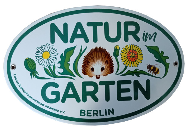 Ovales Email-Schild mit der Aufschrift Natur im Garten. Im Zentrum des Bildes ist in naiver Malweise ein Igel abgebildet. Recht und links neben dem Igel sind Löwenzahnblüten und Blätter sowie ein Hummel gemalt. Am linken unteren Bildrand steht der Schriftzug: Landschaftspflegeverband Spandau e. V. ind unten im Zentrum des Randers in Großbuchstaben Berlin.
